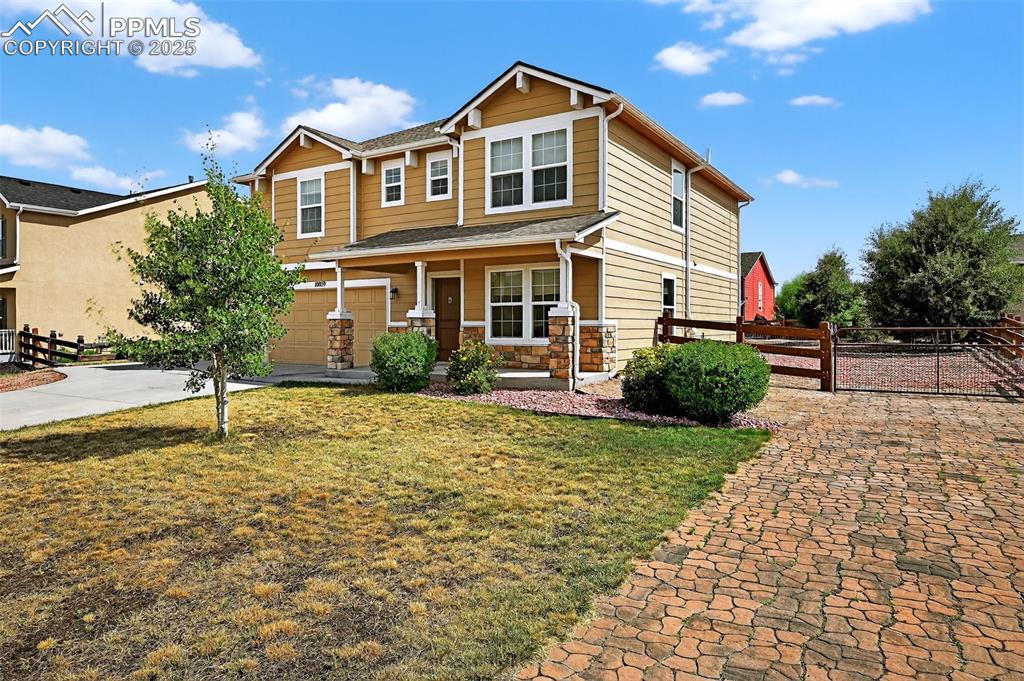 Image 2 of 33: Craftsman-style home with a porch, a garage, stone siding, and concrete dri
