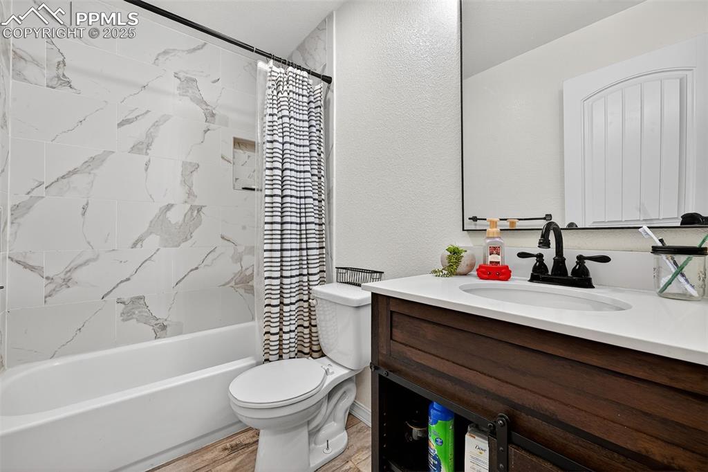 Image 27 of 33: Full bath featuring shower / bath combo with shower curtain, a textured wal