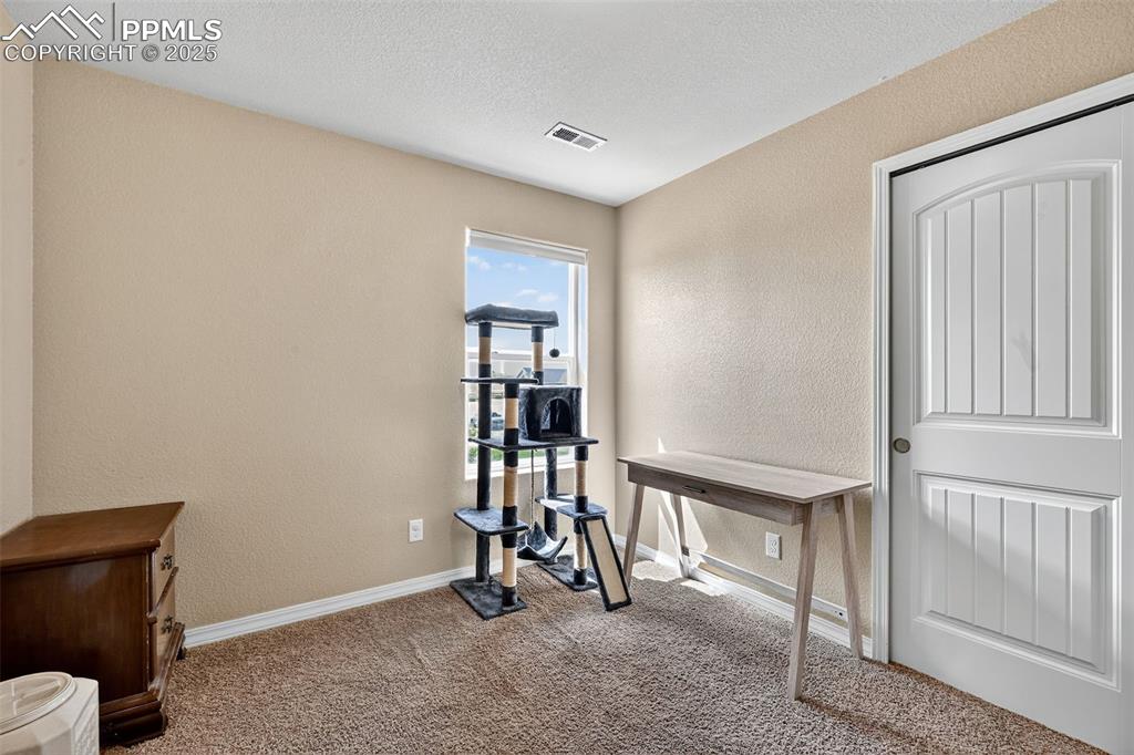 Image 33 of 33: Office area featuring a textured wall, carpet floors, and a textured ceilin