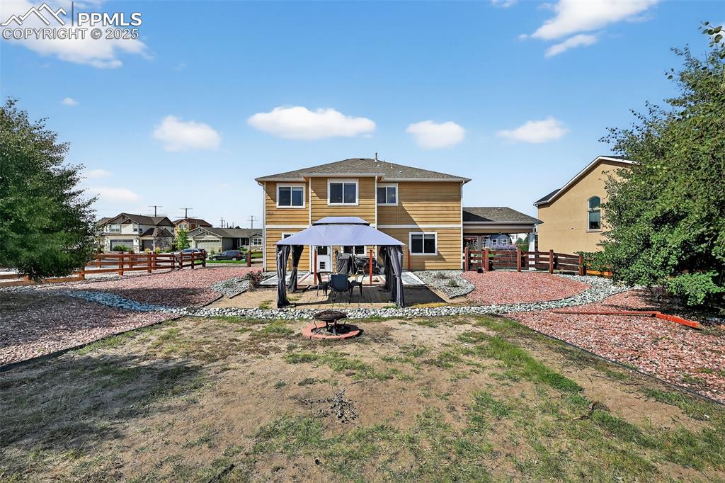 Image 5 of 33: Back of house with a gazebo, a fenced backyard, a fire pit, and a patio are