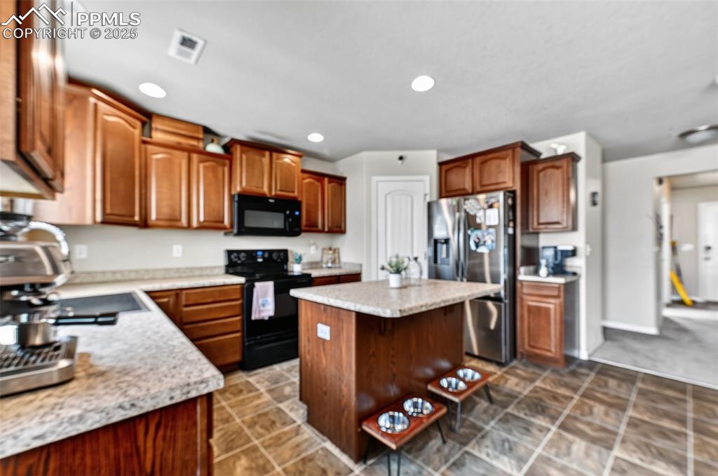 Image 9 of 33: Kitchen featuring black appliances, a center island, recessed lighting, a b