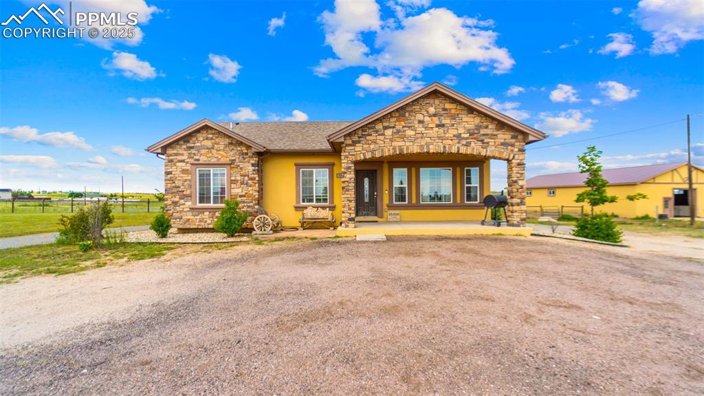Caption: Ranch-style home with stone siding and a shingled roof