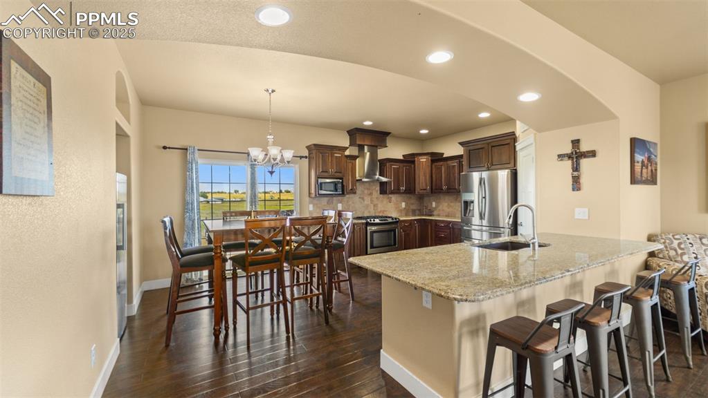 Image 11 of 50: Kitchen featuring stainless steel appliances, a peninsula, decorative backs