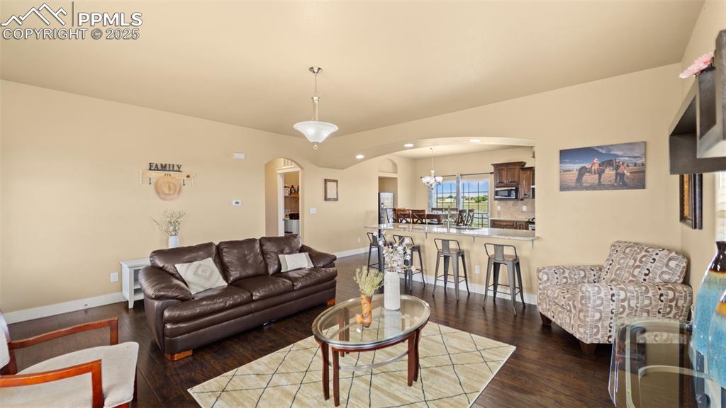 Image 12 of 50: Living area featuring arched walkways, wood finished floors, and recessed l
