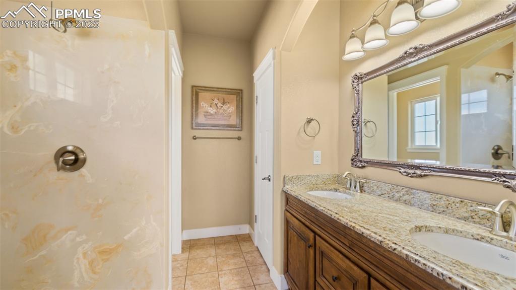 Image 19 of 50: Full bath featuring double vanity, a shower, and tile patterned floors
