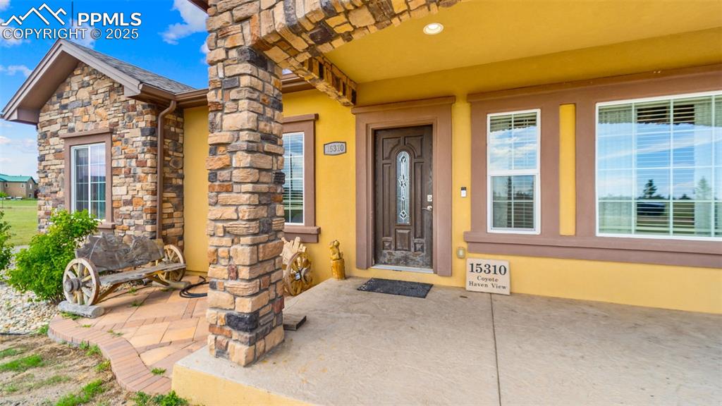 Image 3 of 50: Doorway to property with stone siding and stucco siding
