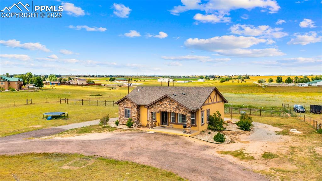 Image 32 of 50: View of front of house featuring driveway, stone siding, covered porch, and
