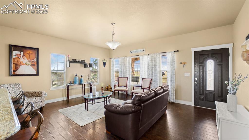 Image 6 of 50: Living area with dark wood-style floors and baseboards