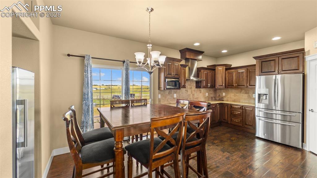 Image 7 of 50: Dining room with dark wood finished floors, a chandelier, and recessed ligh