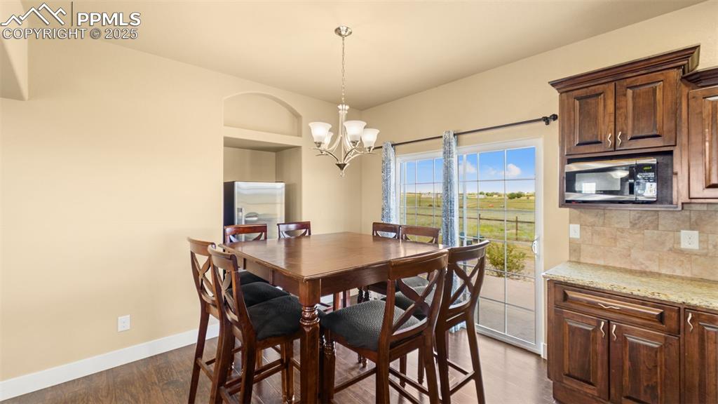 Image 9 of 50: Dining area featuring a chandelier and dark wood-style flooring