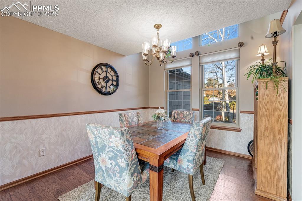 Image 11 of 41: Dining area with hardwood floors, a textured ceiling, classic chandelier, a