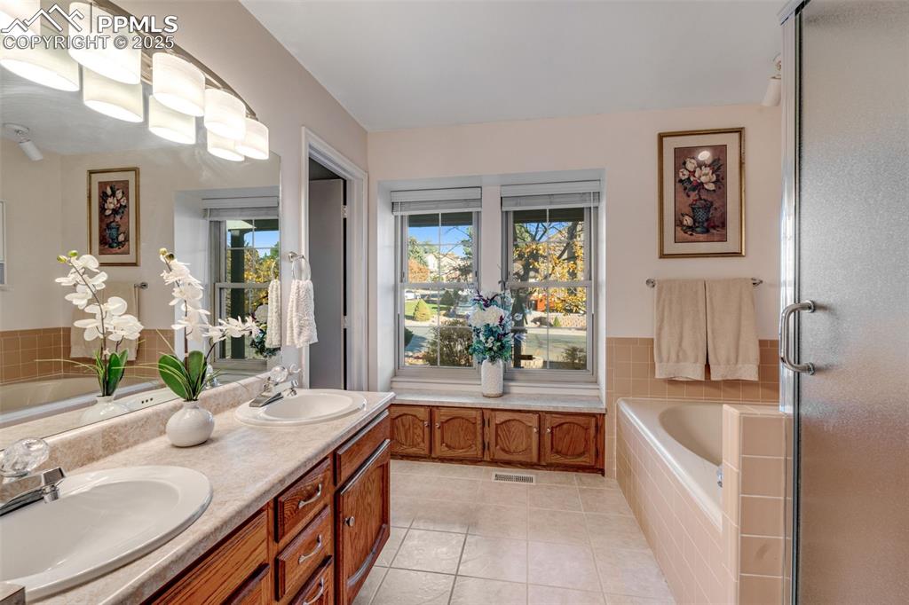 Image 14 of 41: Primary bathroom featuring a bath, free standing shower, double vanity, and