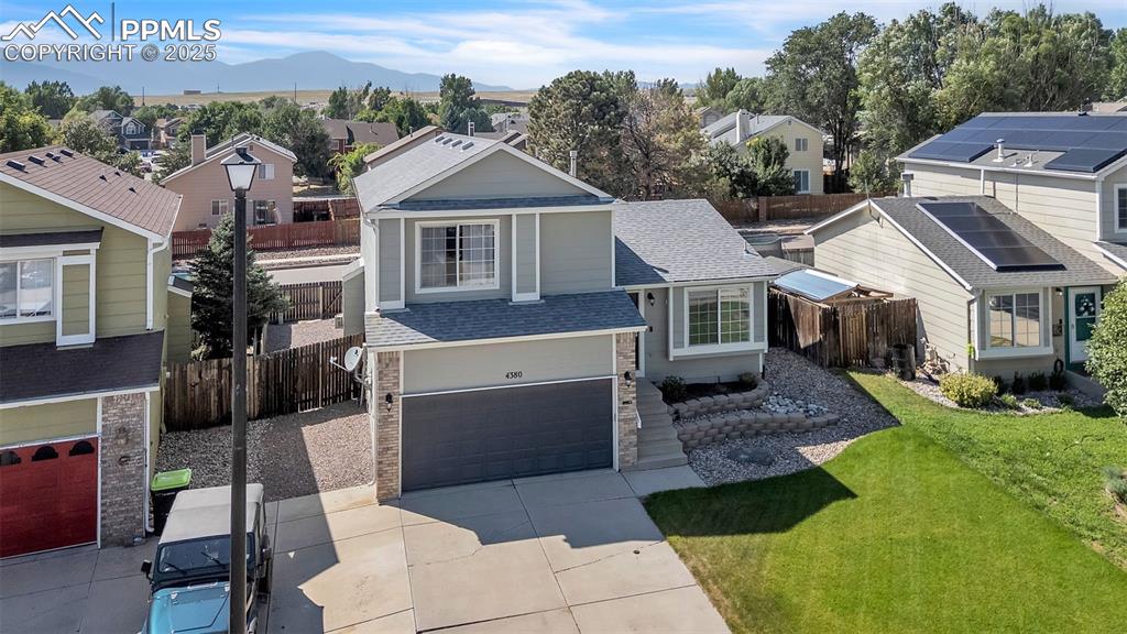 Caption: View of front of property featuring a residential view, a shingled roof, a garage, and driveway