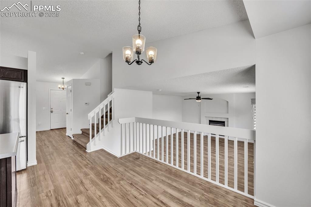 Image 12 of 43: Stairway featuring a chandelier, a fireplace, wood finished floors, a textu