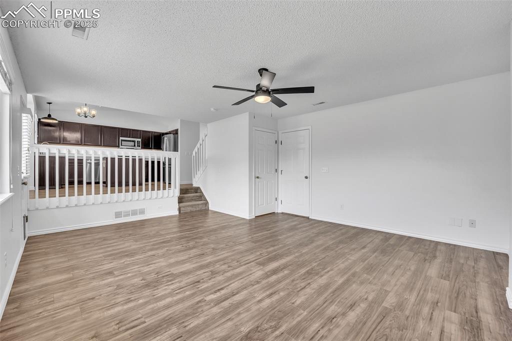 Image 14 of 43: Unfurnished living room featuring light wood finished floors, a textured ce