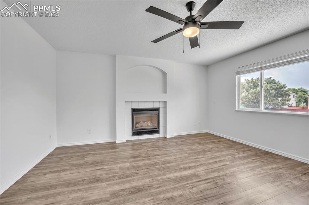 Image 15 of 43: Unfurnished living room with light wood-style floors, a fireplace, a textur