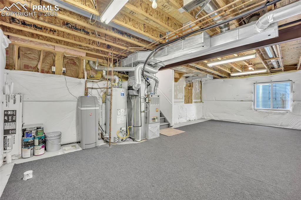 Image 18 of 43: Basement featuring stairway, a water softener, gas water heater, and heatin