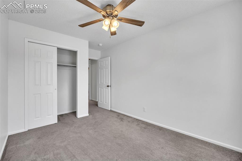 Image 22 of 43: Unfurnished bedroom featuring carpet floors, ceiling fan, a closet, and a t