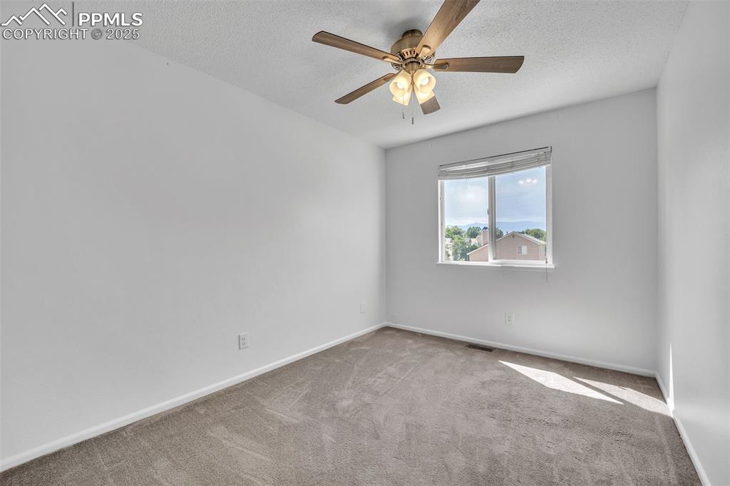 Image 23 of 43: Carpeted empty room with a textured ceiling and ceiling fan