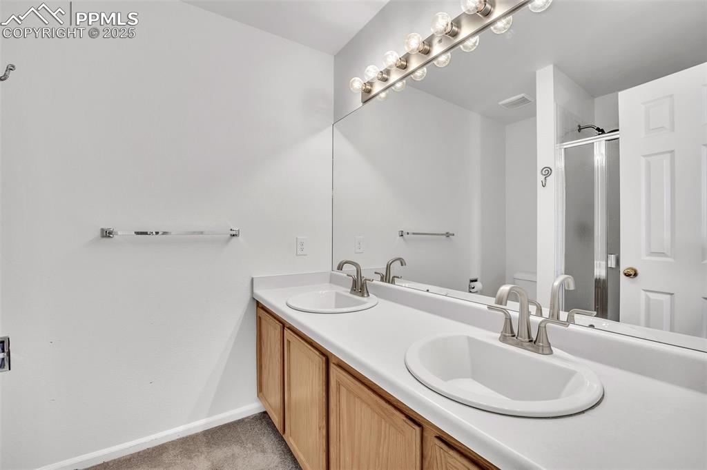 Image 28 of 43: Bathroom with double vanity and a shower stall