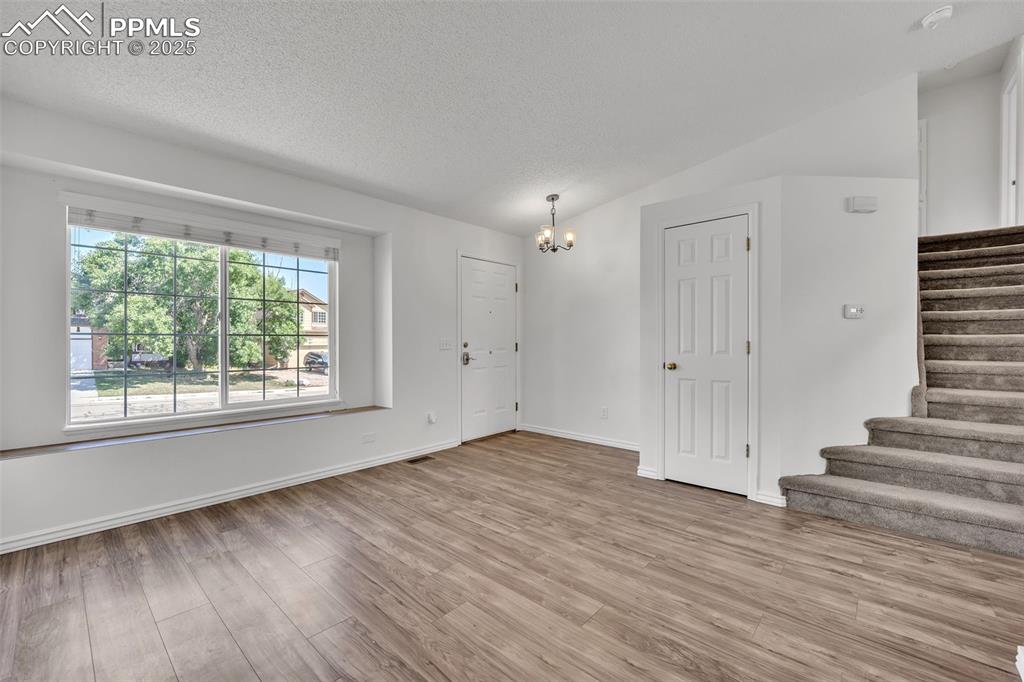 Image 3 of 43: Unfurnished living room featuring a chandelier, a textured ceiling, light w