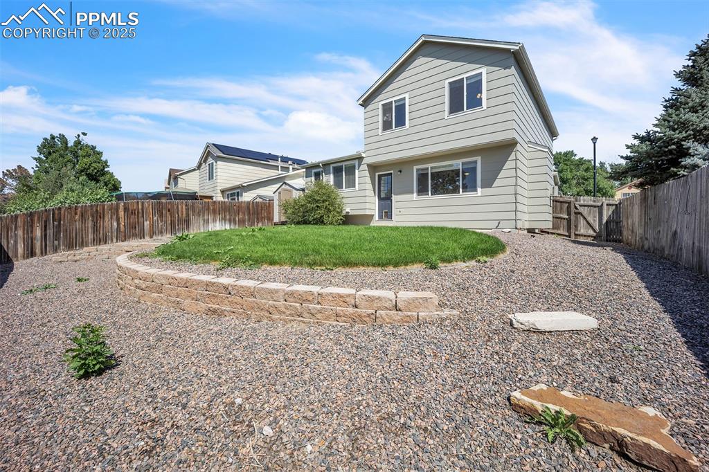 Image 34 of 43: Back of house featuring a fenced backyard and a gate