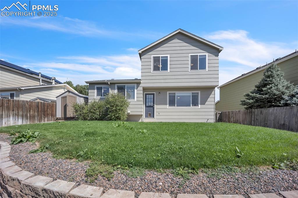 Image 35 of 43: Split level home featuring a fenced backyard and a shed