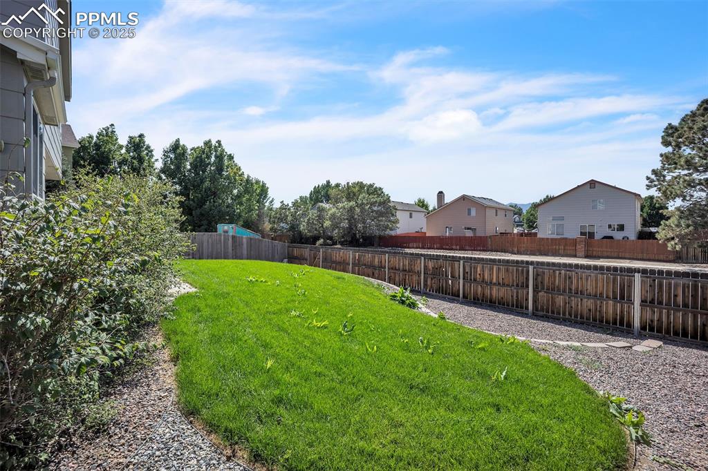 Image 36 of 43: Fenced backyard with a residential view