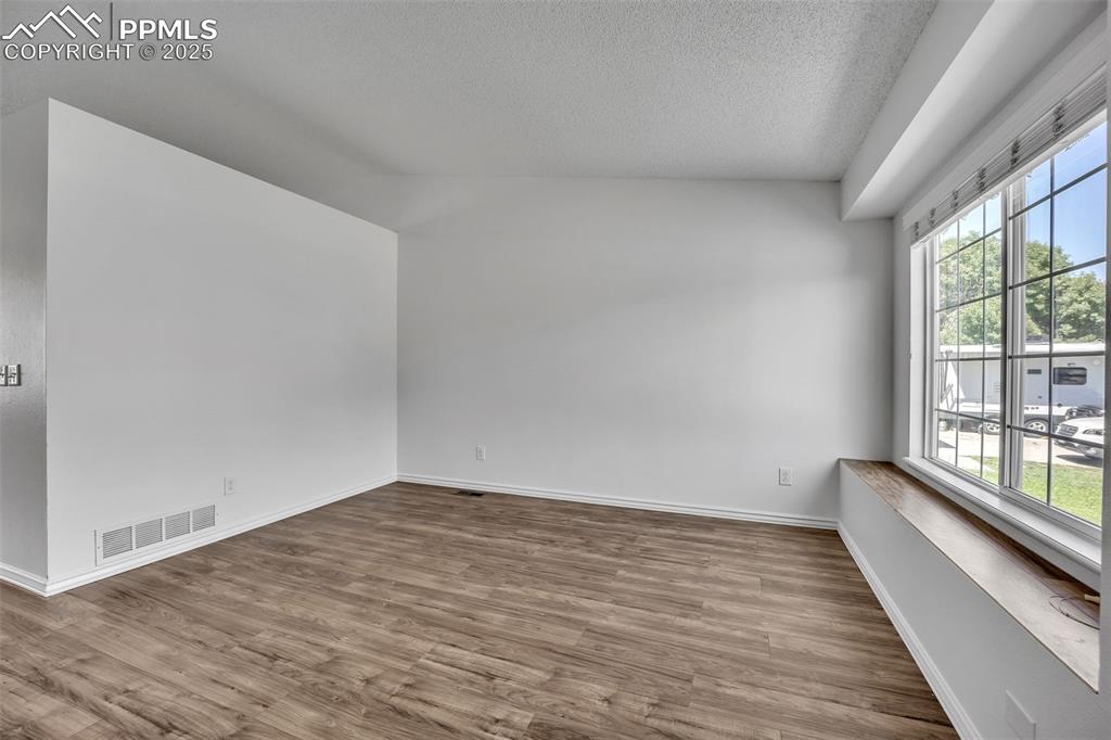 Image 6 of 43: Empty room featuring wood finished floors and a textured ceiling