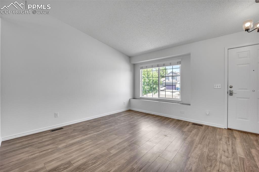 Image 7 of 43: Foyer with wood finished floors, a textured ceiling, and vaulted ceiling