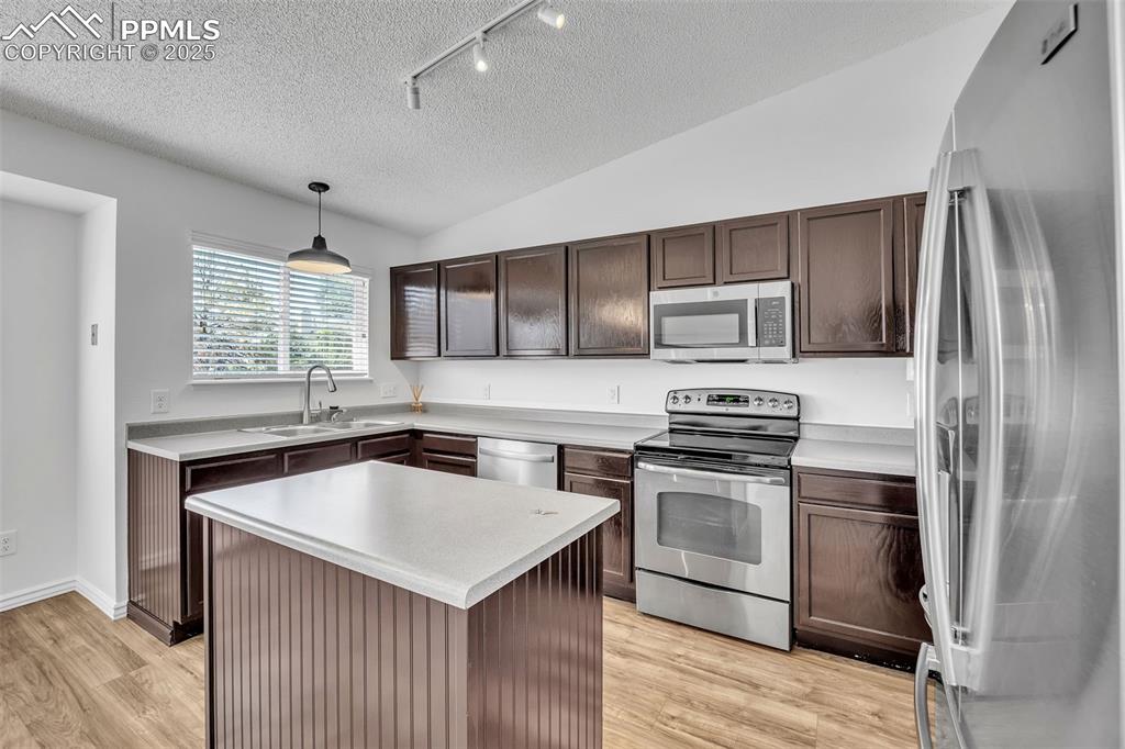 Image 8 of 43: Kitchen with stainless steel appliances, rail lighting, a textured ceiling,