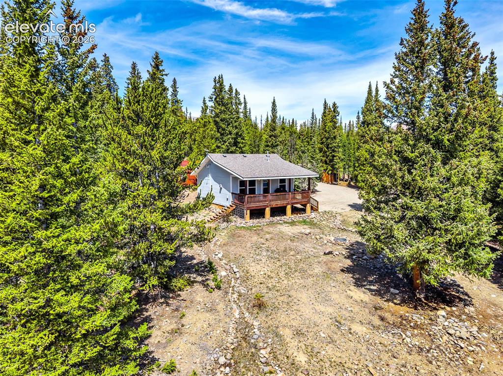 Image 1 of 37: Elevated single-story residence with a covered front porch, set among matur
