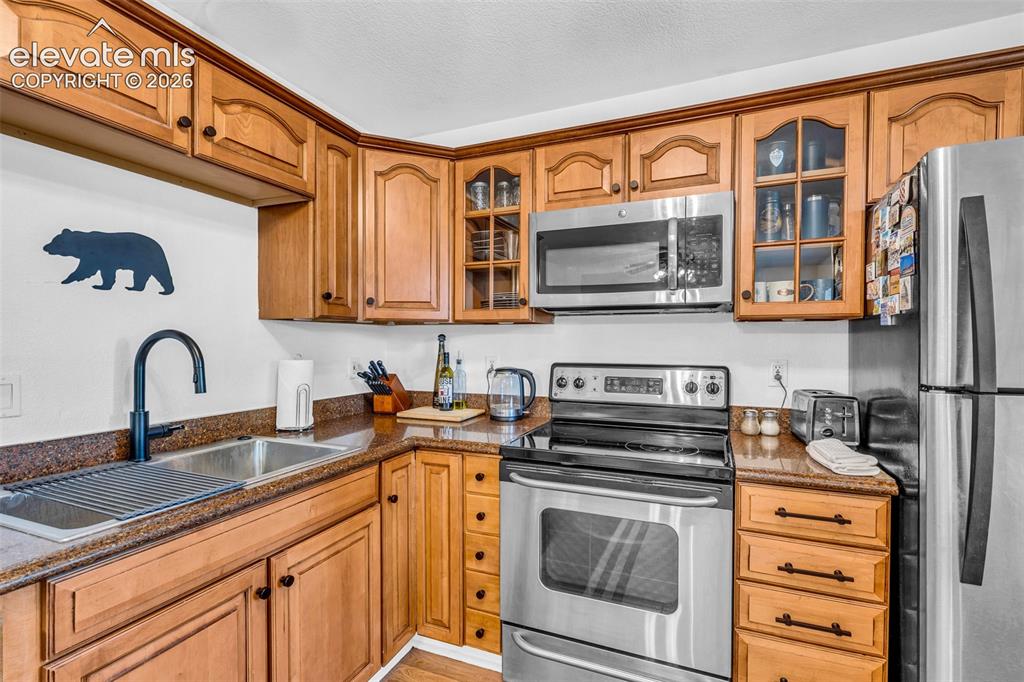 Image 11 of 37: Kitchen featuring wood cabinetry, stainless steel appliances, a corner sink