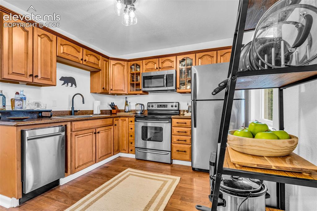 Image 12 of 37: Kitchen featuring wood-finish cabinetry, stainless steel appliances, a dark