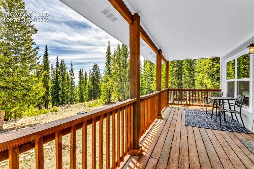 Image 22 of 37: Covered deck with natural wood flooring and railing, supported by timber po