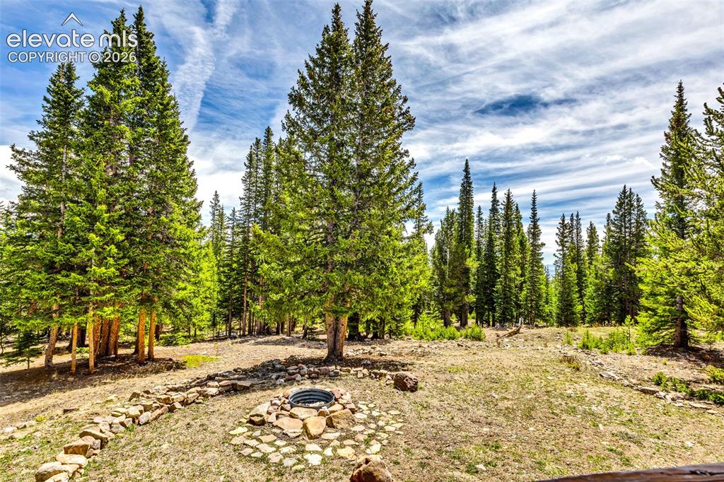 Image 27 of 37: Expansive outdoor space featuring a built-in fire pit with stone surround, 
