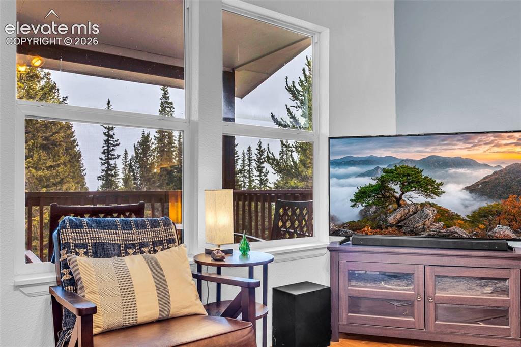 Image 4 of 37: Living area featuring large windows, a light-colored wall, and wood-finish 