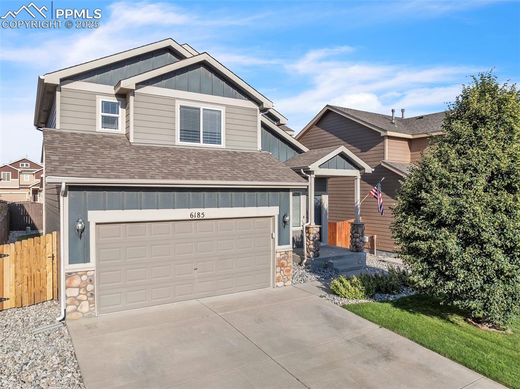 Caption: Craftsman inspired home with board and batten siding, an attached garage, driveway, roof with shingl