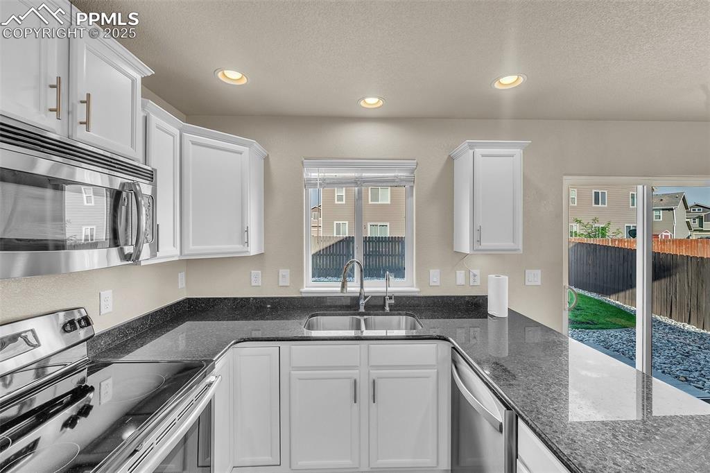 Image 13 of 28: Kitchen with appliances with stainless steel finishes, white cabinets, rece