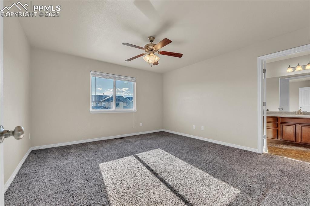 Image 19 of 28: Unfurnished bedroom with carpet flooring, ensuite bath, and a ceiling fan