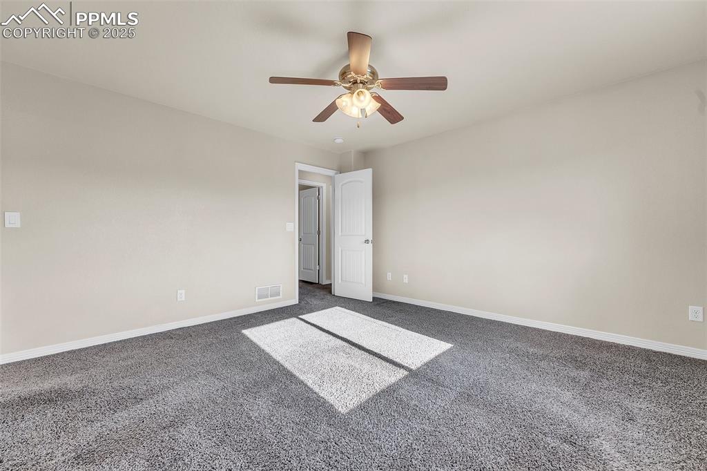 Image 20 of 28: Spare room with dark carpet and ceiling fan