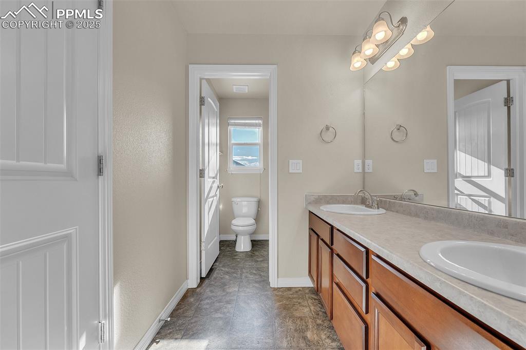 Image 21 of 28: Bathroom with double vanity and toilet