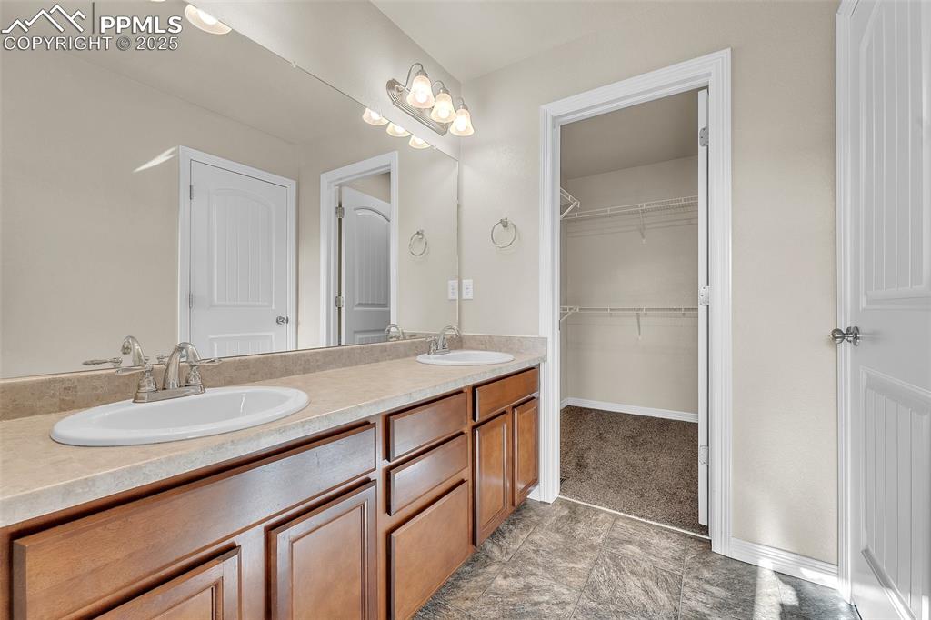 Image 22 of 28: Full bathroom with double vanity and a walk in closet