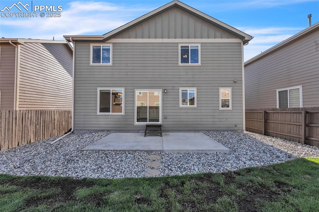 Image 27 of 28: Back of property with a fenced backyard, board and batten siding, and a pat