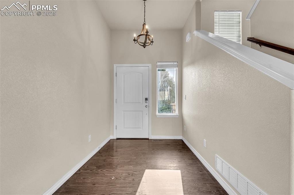 Image 4 of 28: Entryway featuring a chandelier and dark wood-style flooring