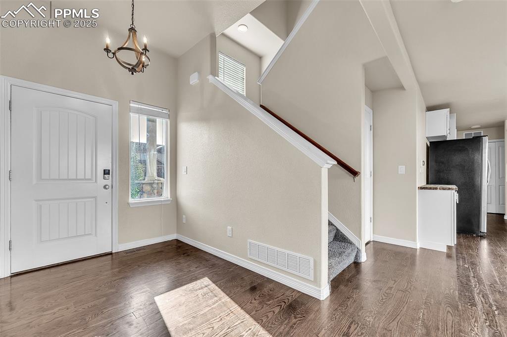 Image 5 of 28: Entrance foyer with stairway, a chandelier, and dark wood finished floors