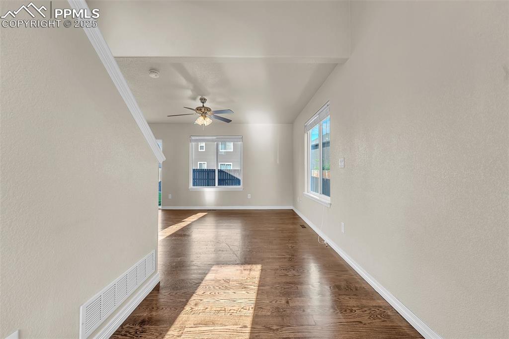 Image 6 of 28: Unfurnished living room with dark wood-style flooring and ceiling fan