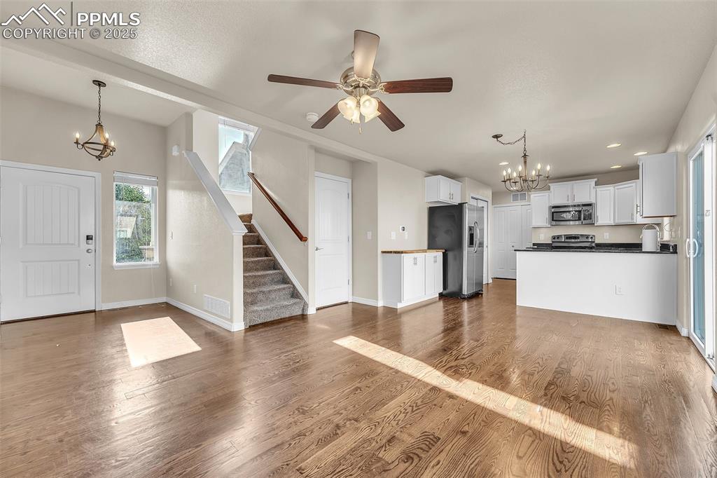 Image 7 of 28: Unfurnished living room with a chandelier, stairs, recessed lighting, dark 