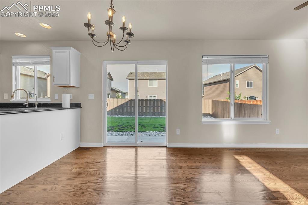 Image 9 of 28: Unfurnished dining area featuring wood finished floors, a chandelier, and r