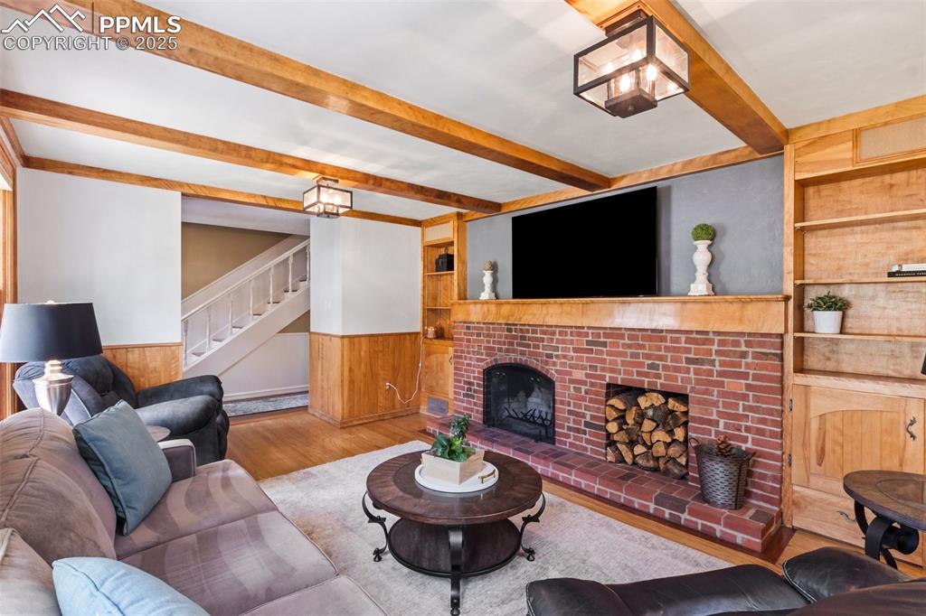 Image 16 of 50: Living room with built in bookcases, wood floors, a wood burning fireplace,